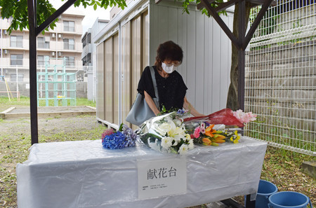 松本サリン事件後、初めて町会が設置した献花台に花を供える女性＝２６日午前、長野県松本市