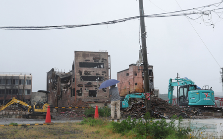 地震で焼失した朝市通り周辺の様子を見詰める人＝６月３０日、石川県輪島市