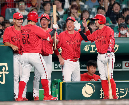 延長１１回、先制の犠飛を放った小園（左から２人目）を迎える広島の新井監督（同４人目）ら＝２０日、甲子園