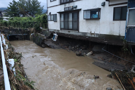 大雨の影響で土台部分が崩れた住宅＝２５日午後、秋田県にかほ市