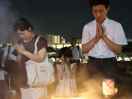 ７９回目の原爆忌を迎える朝、平和記念公園の原爆死没者慰霊碑を訪れ、手を合わせる人たち＝６日午前、広島市中区