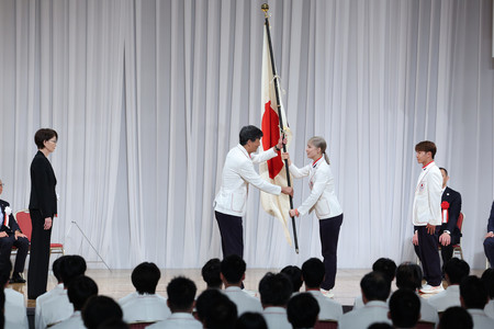 パリ五輪の日本代表選手団の解団式で尾県貢団長（中央左）に団旗を手渡す旗手の江村美咲（同右）。右端は半井重幸＝１４日午前、東京都港区