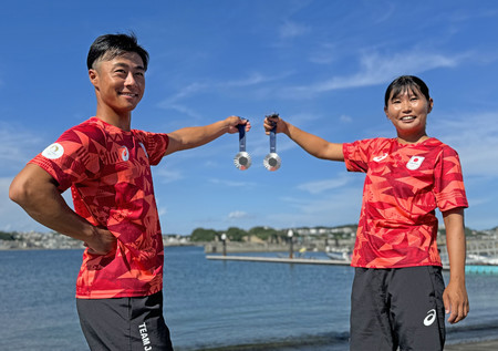 パリ五輪の銀メダルを手に、撮影に応じるセーリング混合４７０級の岡田奎樹（左）と吉岡美帆＝２０日、神奈川県藤沢市江の島ヨットハーバー