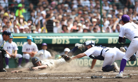 ９回表神村学園２死一、二塁、玉城の中前打で二塁走者の岩下（左）が本塁を突くもタッチアウト。関東一の捕手は熊谷＝２１日、甲子園