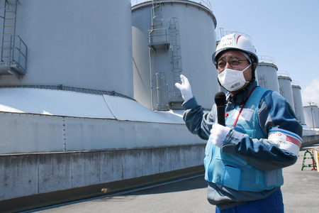 処理水放出で空になったタンクの前で説明する東京電力の担当者。早ければ来年から解体が始まる＝９日、福島県大熊町（代表撮影）