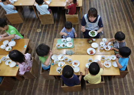 横浜市の認可保育所で、昼食を取る園児と保育士（ＡＦＰ時事）（資料）