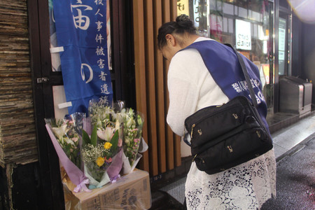 火災が発生した雑居ビルのあった場所に花を手向ける遺族の植田安子さん＝３１日午後、東京都新宿区