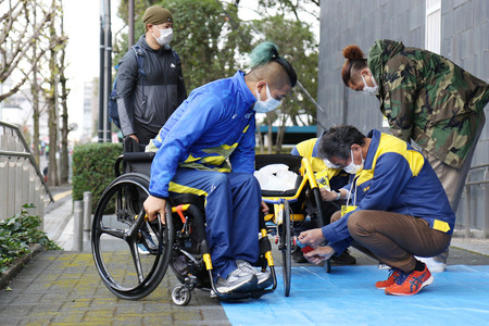 パラ陸上の佐藤友祈選手（手前左）と、レース用車いすの製造などを担当するオーエックスエンジニアリングの小沢徹さん（同右）＝２０２２年１１月（同社提供）