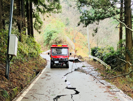 ひび割れがある道路を走って、能登半島地震の被災現場に向かう消防の小型救助車（総務省消防庁提供）