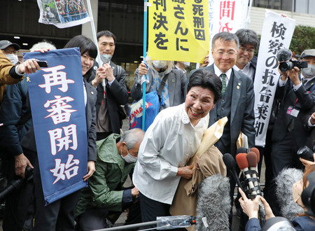 袴田巌さんの第２次再審請求差し戻し審で、「再審開始」などと書かれた垂れ幕の前で笑顔を見せる姉ひで子さん（中央）ら＝２０２３年３月、東京都千代田区