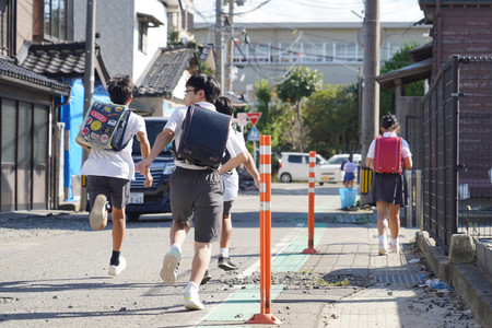 大雨による臨時休校が明け、再開した学校から帰る小学生＝２６日午後、石川県輪島市