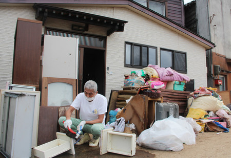 泥で汚れた家財道具を洗う山崎政信さん＝２８日午後、石川県輪島市