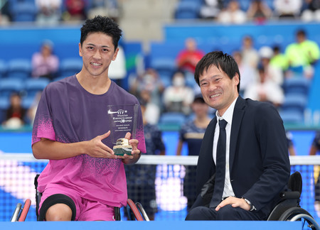 車いすのシングルスで優勝し、国枝慎吾さん（右）からトロフィーを受け取った小田凱人＝２９日、東京・有明テニスの森公園