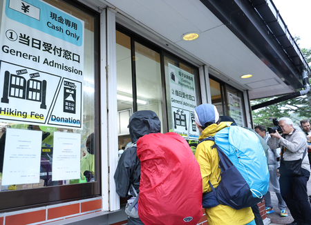 富士山五合目総合管理センターの窓口で入山手続きをする登山客ら＝７月１日、山梨県富士吉田市