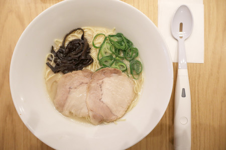 一風堂で販売する塩分３０％オフのラーメン「減塩白丸元味」とキリンホールディングスが開発した塩味を補う「エレキソルト　スプーン」＝３日午後、東京都港区