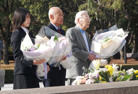 平和記念公園にある原爆死没者慰霊碑に献花し、ノーベル平和賞受賞を報告する日本被団協代表委員の箕牧智之さん（中央）ら＝１８日午前、広島市中区