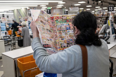 東京都内のスーパーの店内で、チラシをチェックする女性（ＡＦＰ時事）