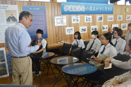 東日本大震災で被災し再建された「ゆりあげ港朝市」の桜井広行代表理事（左端）から話を聞く輪島高校の生徒＝９月２８日、宮城県名取市