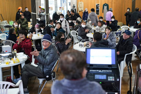 珠洲市役所前の「飯田わくわく広場」で行われたカラオケ大会で、盛り上がる地元の人たち＝３１日午後、石川県