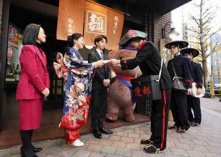 創業時などの制服姿で年賀状を配達する郵便局員ら＝１日午前、東京都新宿区