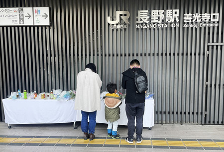 ＪＲ長野駅前で起きた殺傷事件を受け設置された献花台で手を合わせる家族＝２６日午前、長野市