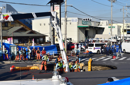 県道交差点の陥没現場で、転落したトラック運転手の救出作業に当たる消防隊員ら＝２８日午後、埼玉県八潮市