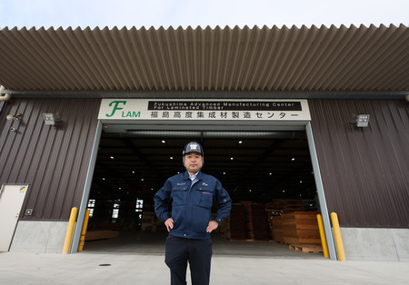 新工場の「福島高度集成材製造センター(FLAM)」の前で撮影に応じるウッドコア取締役の朝田英洋さん=2024年12月11日、福島県浪江町