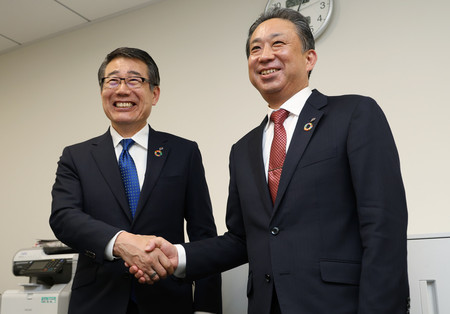 笑顔で握手するセブン―イレブン・ジャパンの永松文彦社長(左)と阿久津知洋次期社長=17日午後、東京・丸の内