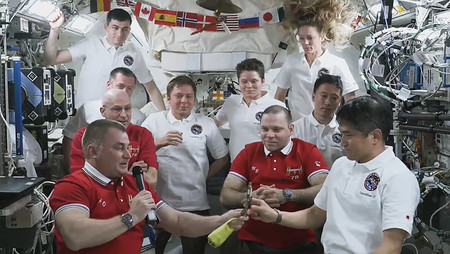 国際宇宙ステーション(ISS)の船長引き継ぎ式で、前任からISSの指揮権を象徴する「鍵」を受け取る大西卓哉さん(前列右)=日本時間19日(NASA提供)