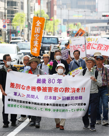 戦争被害者の救済を求めて行進する人たち=19日午後、東京都中央区