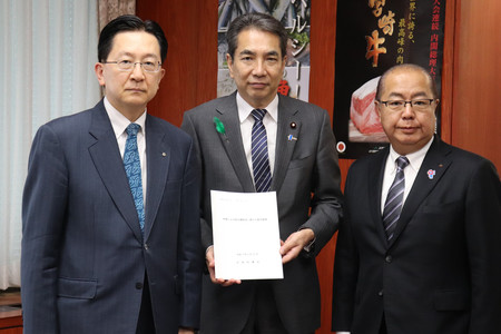 米国の関税措置に関し、達増拓也岩手県知事(左)らから全国知事会の緊急要請書を受け取った江藤拓農林水産相(中央)=22日午前、東京都千代田区