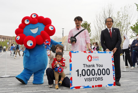 大阪・関西万博で１００万人目の来場者として家族とともに記念品を受け取る宮森信さん（右から２人目）＝２３日午後、大阪市此花区