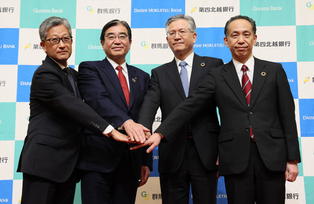 経営統合で基本合意し、撮影に応じる群馬銀行の深井彰彦頭取（中央左）と第四北越フィナンシャルグループ（ＦＧ）の殖栗道郎社長（同右）ら＝２４日午後、東京都港区