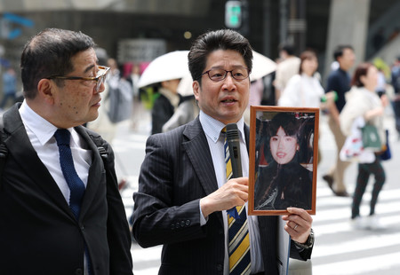 拉致被害者の有本恵子さんの写真を手に、北朝鮮による拉致問題の解決を訴える家族会代表の横田拓也さん(右)=26日午前、東京都中央区