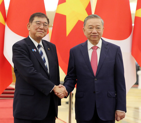ベトナムのトー・ラム共産党書記長(右)と握手する石破茂首相=27日、ハノイ(EPA時事)