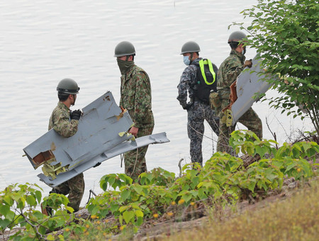 自衛隊機が墜落した入鹿池で、回収した機体の一部とみられる破片を運ぶ自衛隊員=15日午前、愛知県犬山市