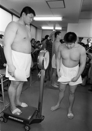 新弟子検査で貴花田(左、後の横綱貴乃花)の体重を見る兄の若花田(後の横綱3代目若乃花)=1988年3月、大阪市