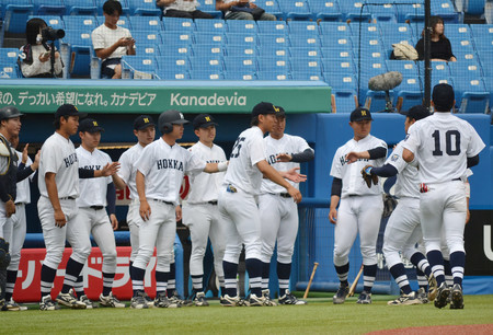 全日本大学野球選手権準々決勝の青学大戦、攻守交代で守備に就いていた選手を出迎える北海学園大のベンチ入りメンバー=13日、神宮球場