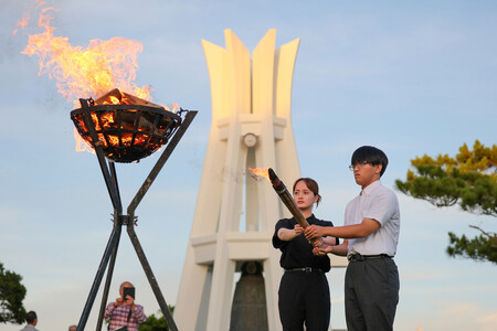沖縄慰霊の日の前夜祭で、火をともす戦没者の遺族代表=22日午後、沖縄県糸満市