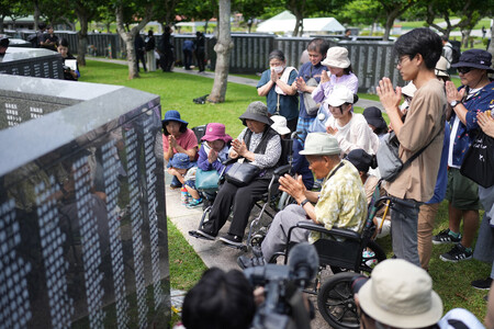 「平和の礎」を訪れ、手を合わせる人たち=23日、沖縄県糸満市の平和祈念公園
