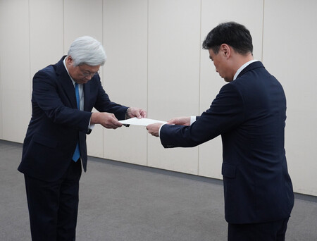 総務省から行政処分を受ける日本郵便の千田哲也社長(左)=25日午後、東京都千代田区