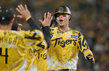 6回、先制の2ランを放ち、ベンチ前でチームメートに迎えられる阪神の佐藤輝=13日、甲子園