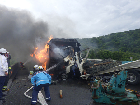 徳島自動車道でトラックと高速バスが衝突し、炎上したバスの消火活動を行う消防隊員ら=14日、徳島県阿波市(同県警提供)