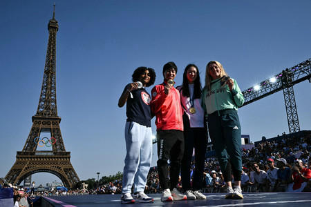 パリ五輪で獲得した金メダルを手にし、エッフェル塔を背に撮影に応じるフェンシング男子エペの加納虹輝(左から2人目)ら=2024年7月、パリ(AFP時事)