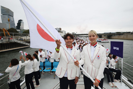 開会式でセーヌ川を進む船上で日の丸を手にする日本選手団旗手の江村美咲（右）と半井重幸＝２６日、パリ（ＡＦＰ時事）