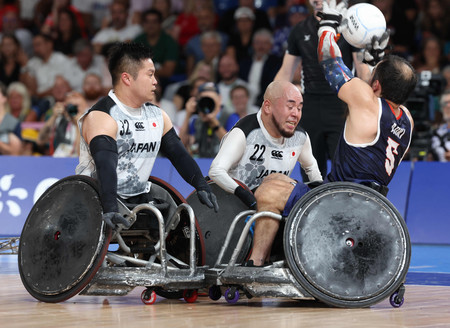 車いすラグビー決勝の米国戦で相手選手をブロックする乗松（中央）＝２日、パリ