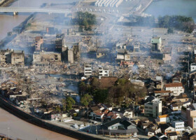 地震による火災が発生し、煙が上がる石川県輪島市の市街地＝２日午前（時事通信チャーター機より）