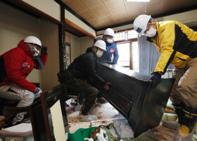 被災した住宅で、倒れた仏壇を持ち上げるボランティア＝１０日午前、石川県輪島市