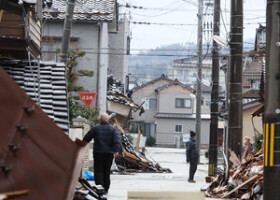 地震の影響によって崩れた家屋と道路に散乱しているがれき＝１０日、石川県輪島市