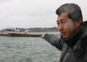 津波で打ち上げられた自身の漁船を指さす漁師の須見広文さん＝５日、石川県能登町